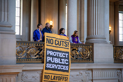 SF City Workers drop large banners in City Hall Rotunda with text that reads: "Protect Public Services. No cuts! No layoffs!"