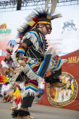 A dancer takes the stage during the Mandan Hidatsa Arikara (MHA) Indian Horse Relay at the 2024 North Dakota State Fair in Minot, ND. The heart-pounding relay, featuring riders racing bareback across three horses, spotlights breathtaking speed, agility, and precision with MHA dancers captivating the crowd between heats. Credit: North Dakota Tourism