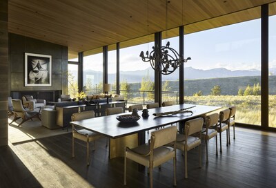 An Albert Watson photograph presides over the great room and a custom walnut-and-metal dining table inlaid with brass droplets beneath a sculptural Frederik Molenschot art chandelier.